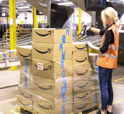  A female warehouse worker scanning a large stack of Amazon boxes in a warehouse.